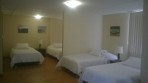 A hotel room with three single beds, a wooden floor, and two wall-mounted lamps. - Hotel Miramonte & apartments (San Salvador)
