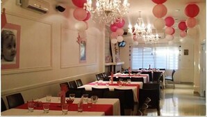 A dining area with tables set for a meal, chandeliers, and red and white balloons. - Hotel Miramonte & apartments (San Salvador)
