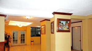 A hotel lobby with a tiled floor, a reception desk, a framed picture on the wall, and a door leading to another room. - Hotel Miramonte & apartments (San Salvador)