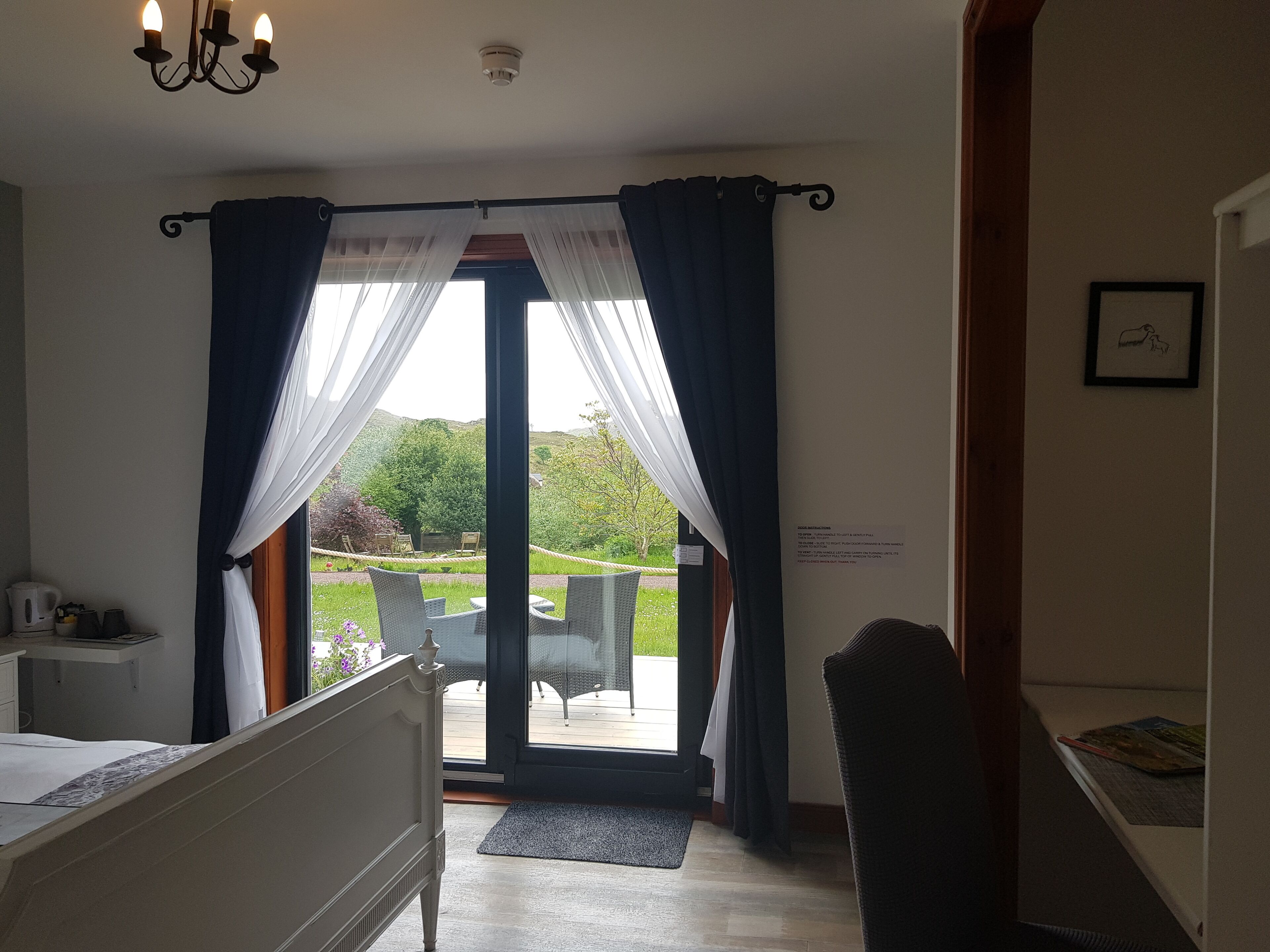 Une chambre avec un lit, un bureau et une vue sur l’extérieur grâce à une porte vitrée.