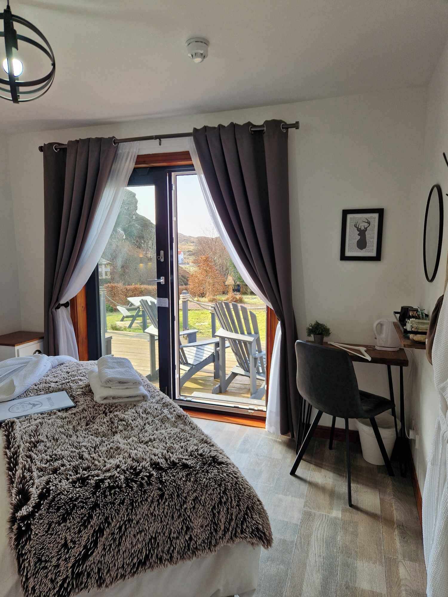 A hotel room with a bed, a desk, a chair, and a view of the outdoors.