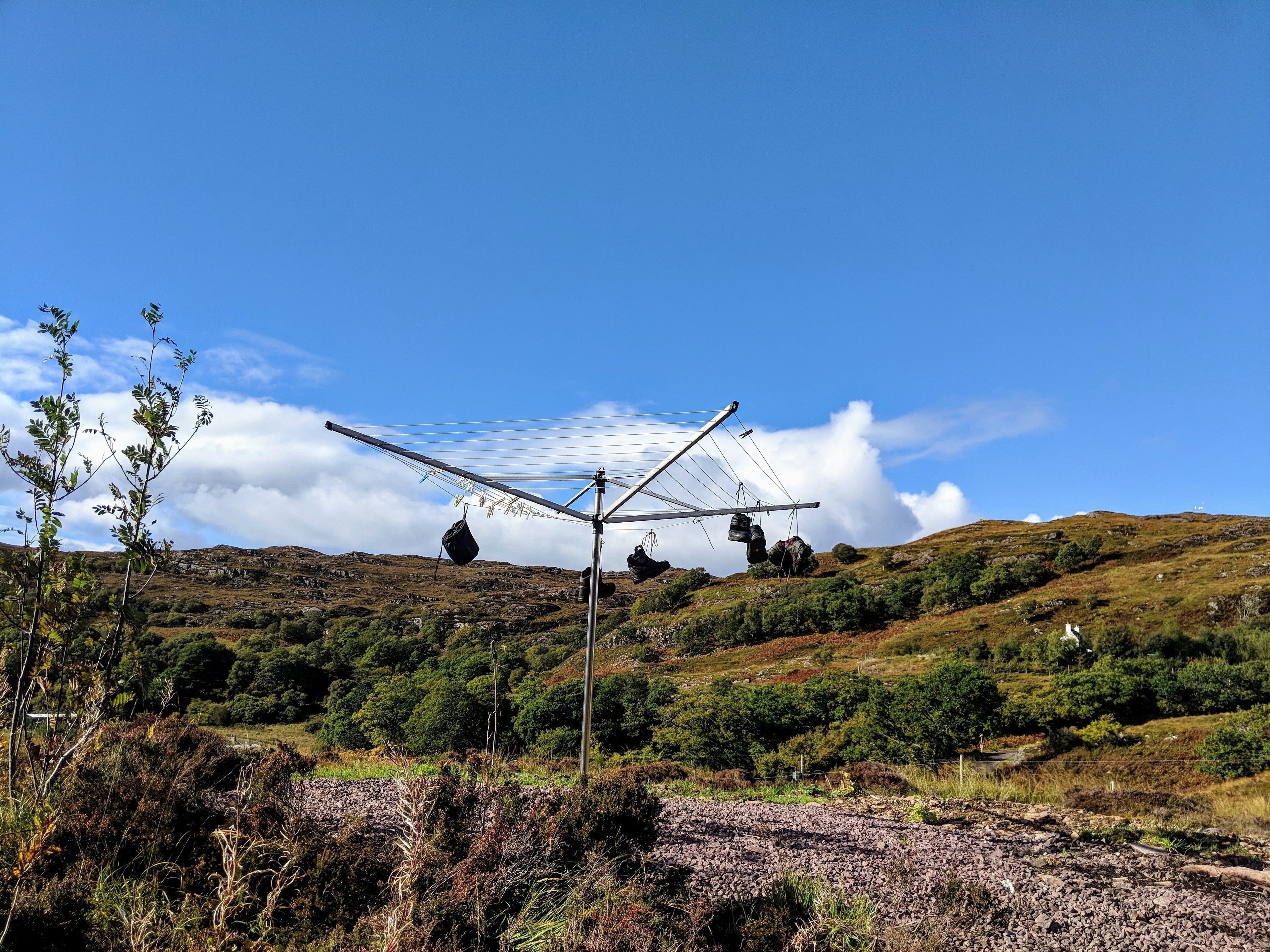 En solpanel med påsar hängande på den, placerad mot en kuperad landskap med gles vegetation.