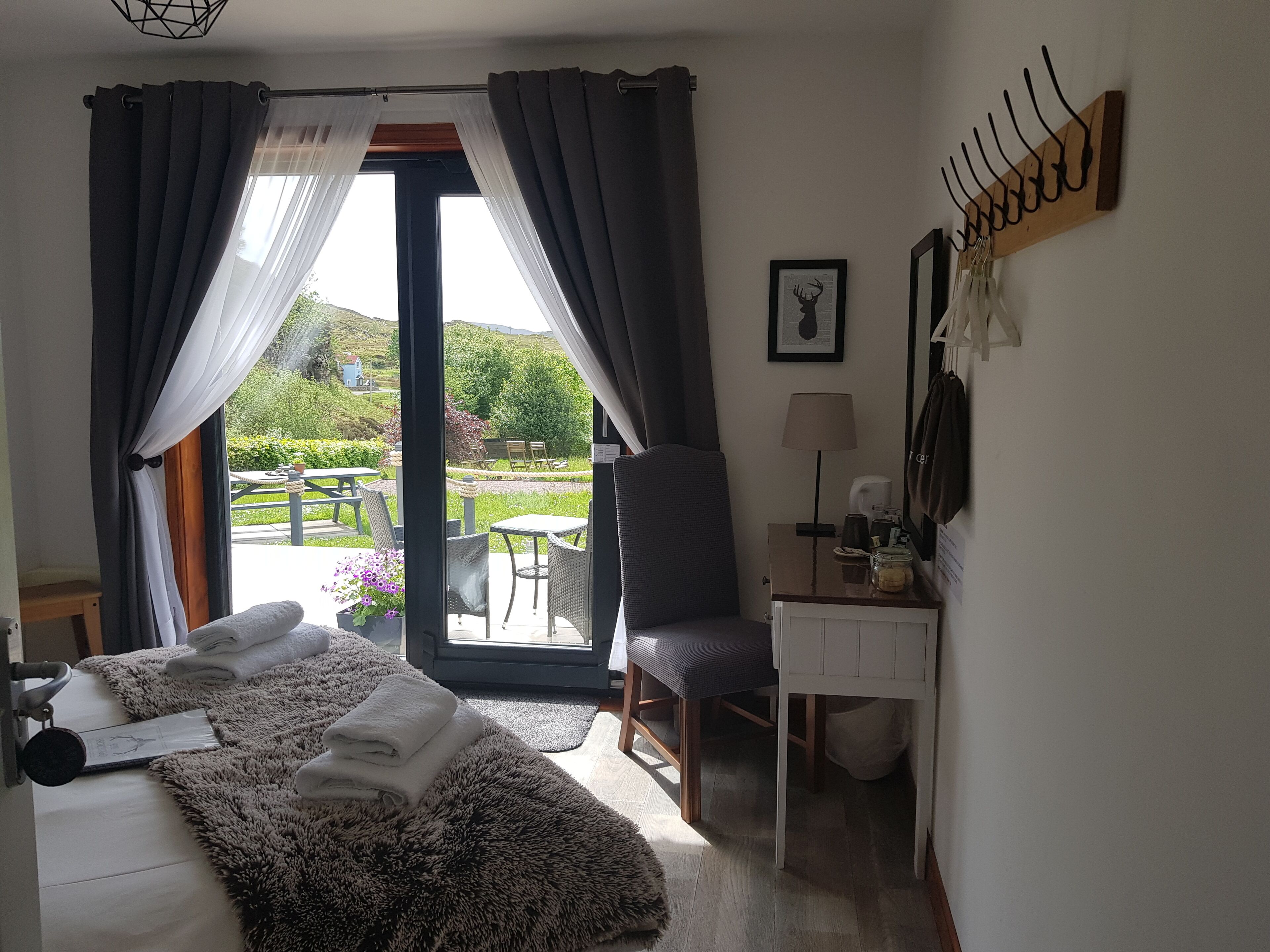 Une chambre d’hôtel équipée d’un lit, d’un bureau, d’une chaise, d’une lampe et offrant une vue sur l’extérieur.
