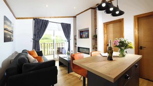 A modern kitchen with a wooden island, a dining area with a table and chairs, and a living room with a sofa. - Applecross B&B and Cabins (Strathcarron)