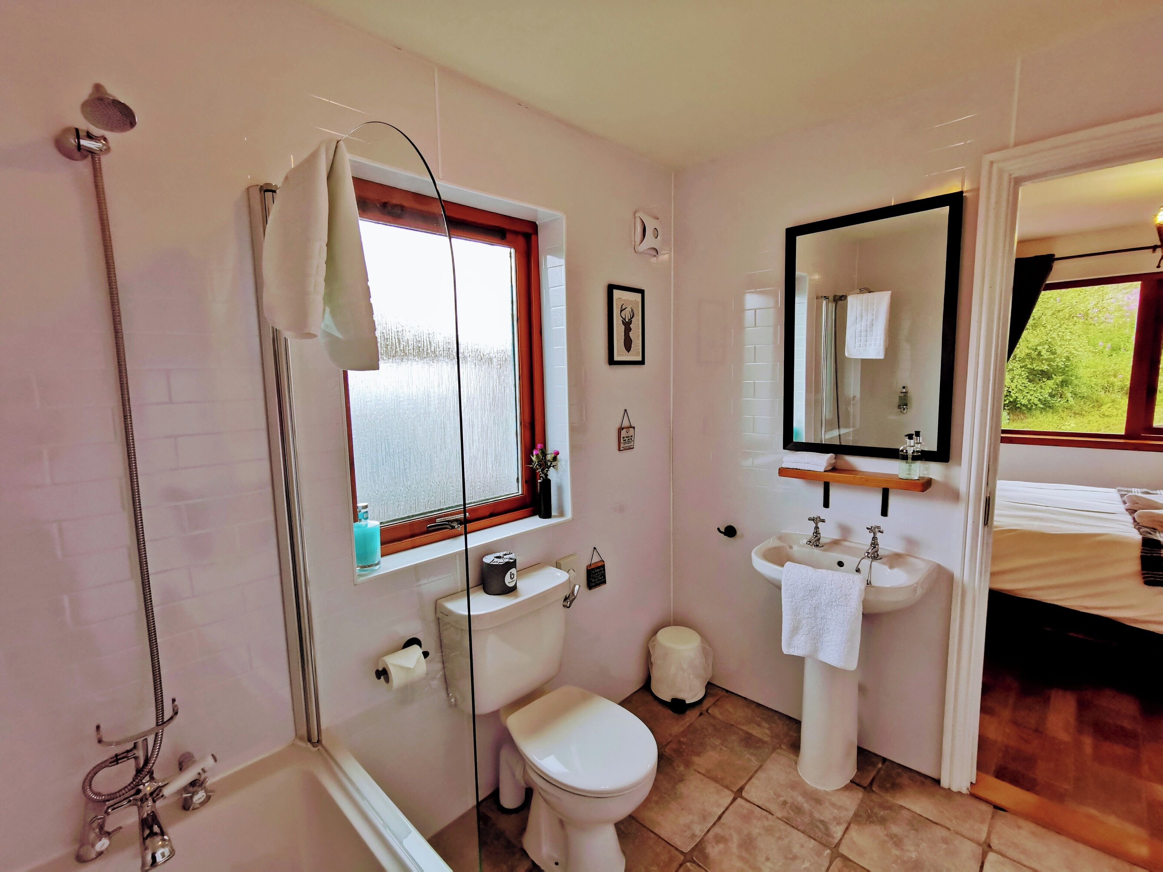 A bathroom with a bathtub, toilet, sink, and a window with a view of greenery.