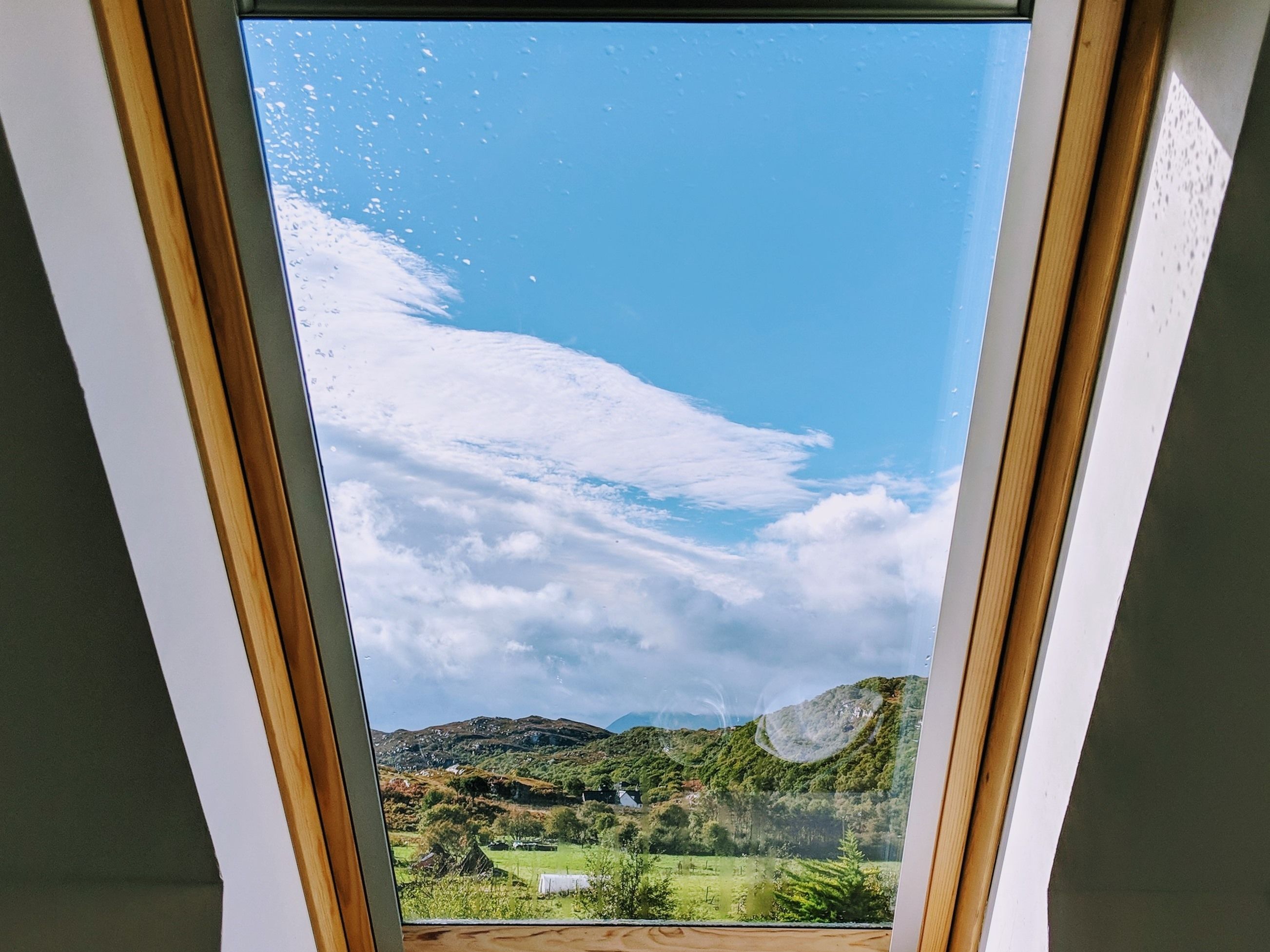 Une lucarne offrant une vue dégagée sur un paysage verdoyant et des collines.