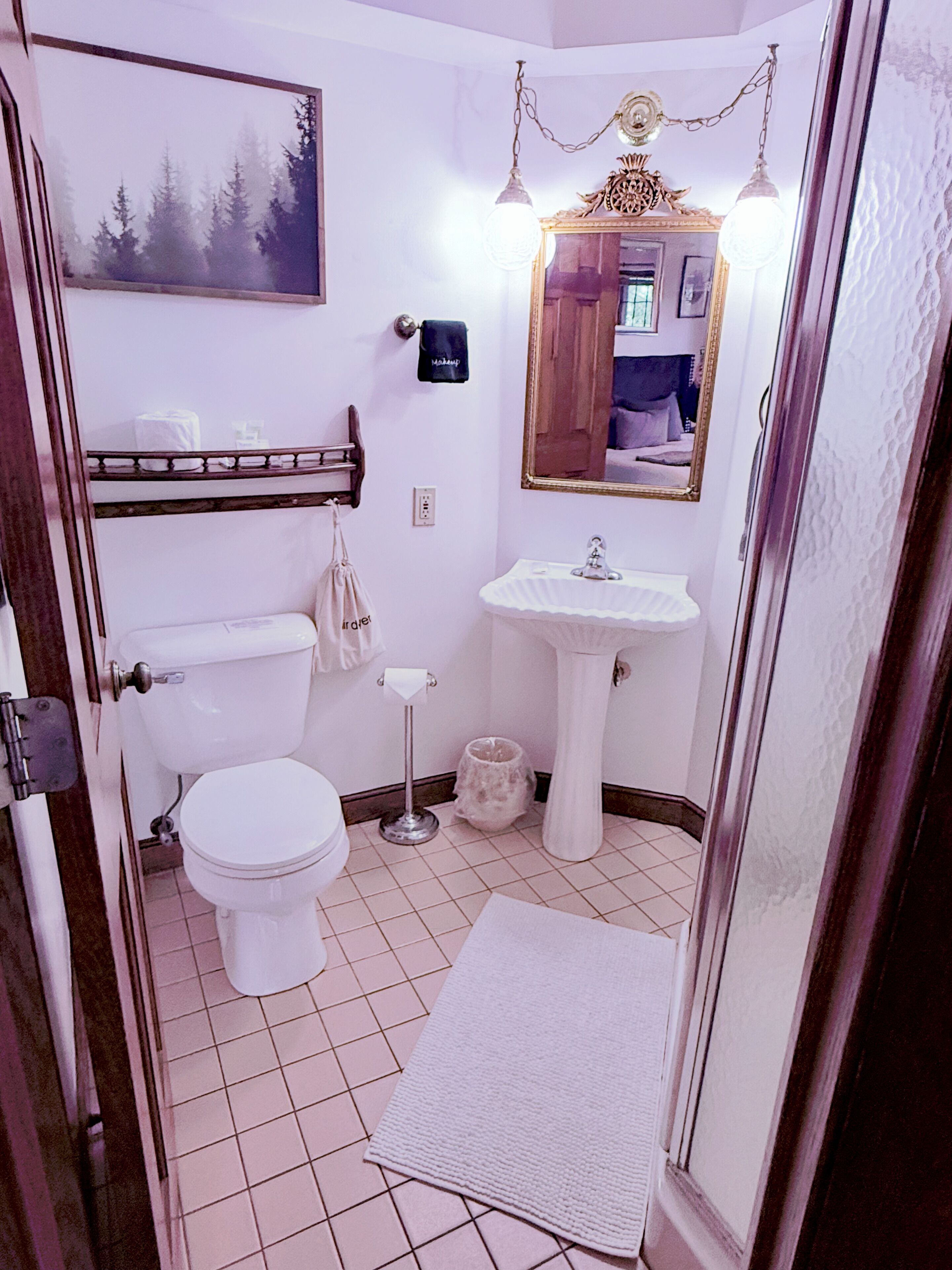 A bathroom with a toilet, sink, and mirror.