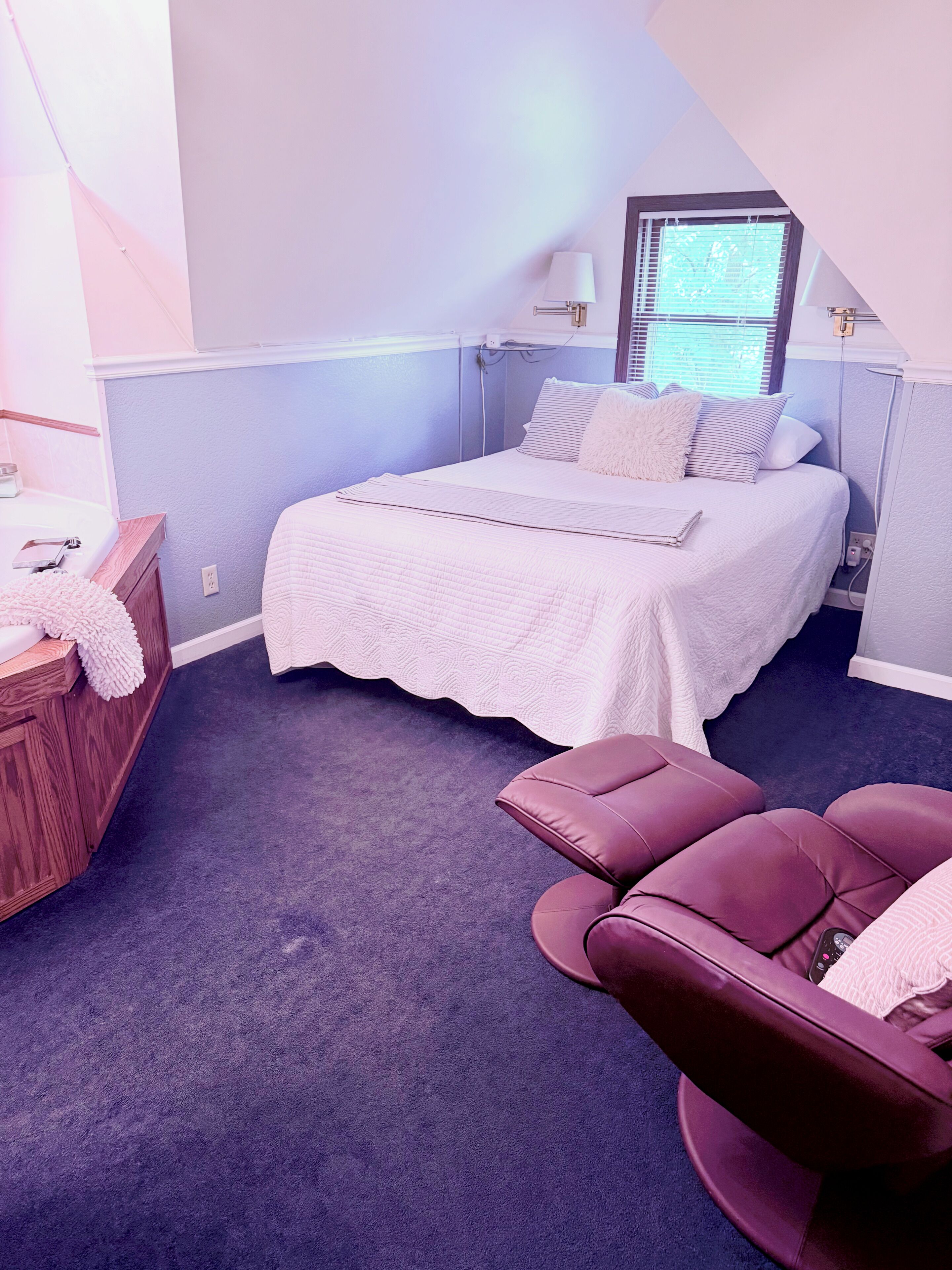 A bedroom with a bed, a bedside table, a chair, and a window.