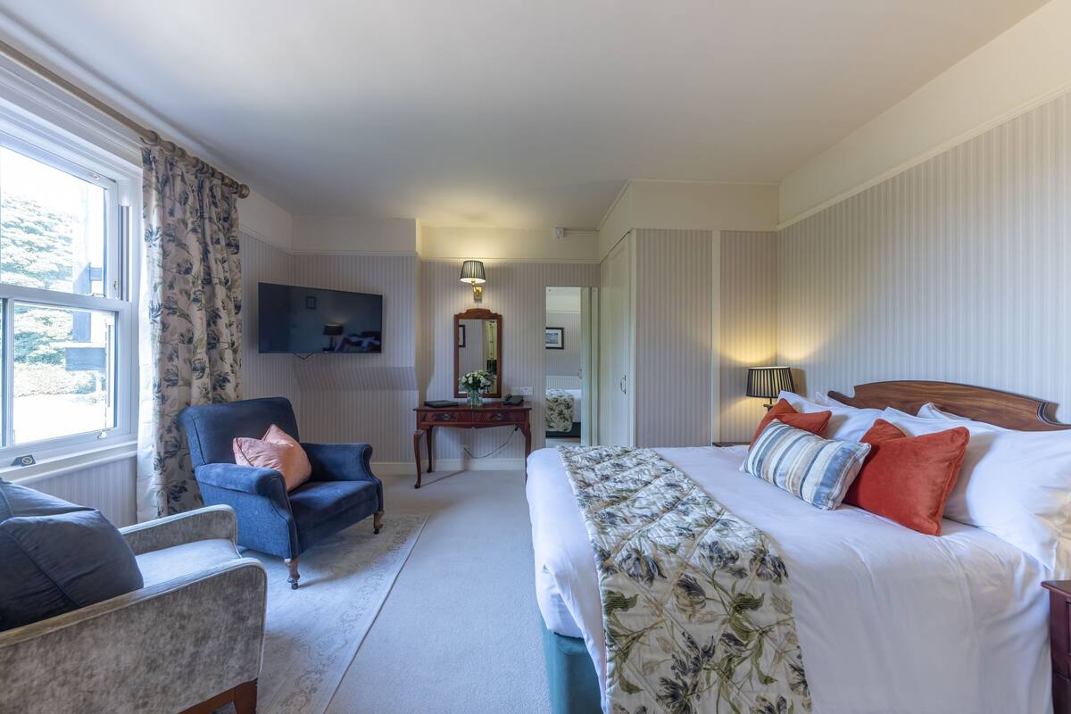 A bedroom with a bed, a chair, a desk, and a television.