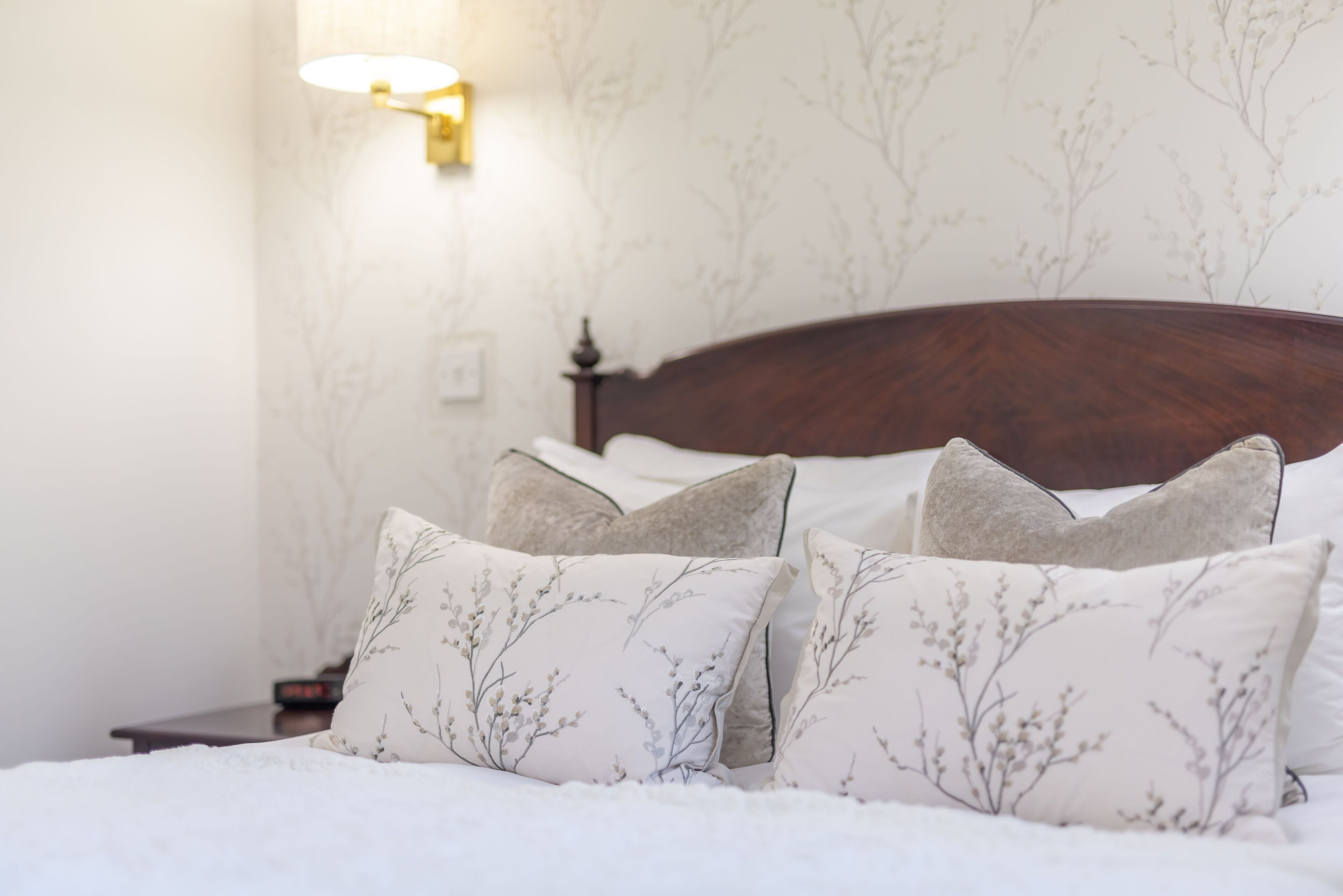 Una cama bien hecha con almohadas de estampado floral y un cabecero de madera.