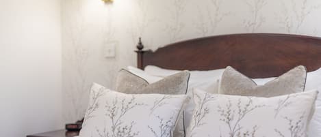 Una cama bien hecha con almohadas de estampado floral y un cabecero de madera.