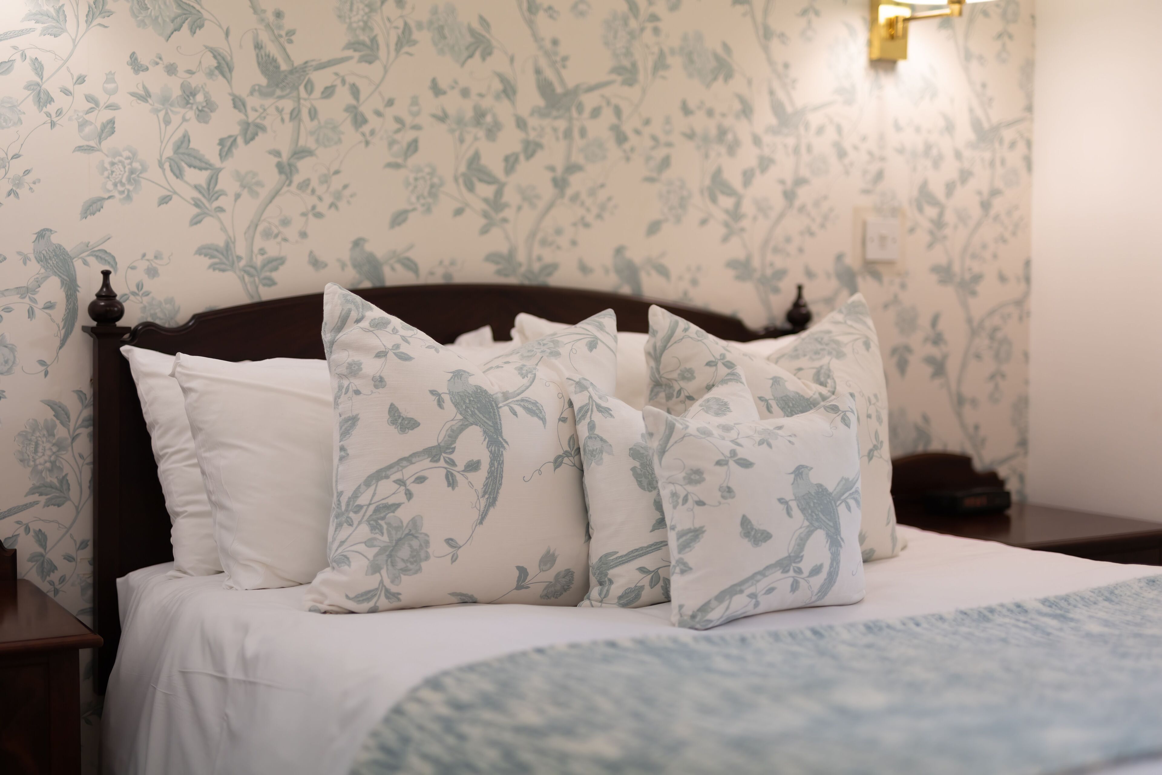 A bed with floral-patterned pillows and a matching headboard.