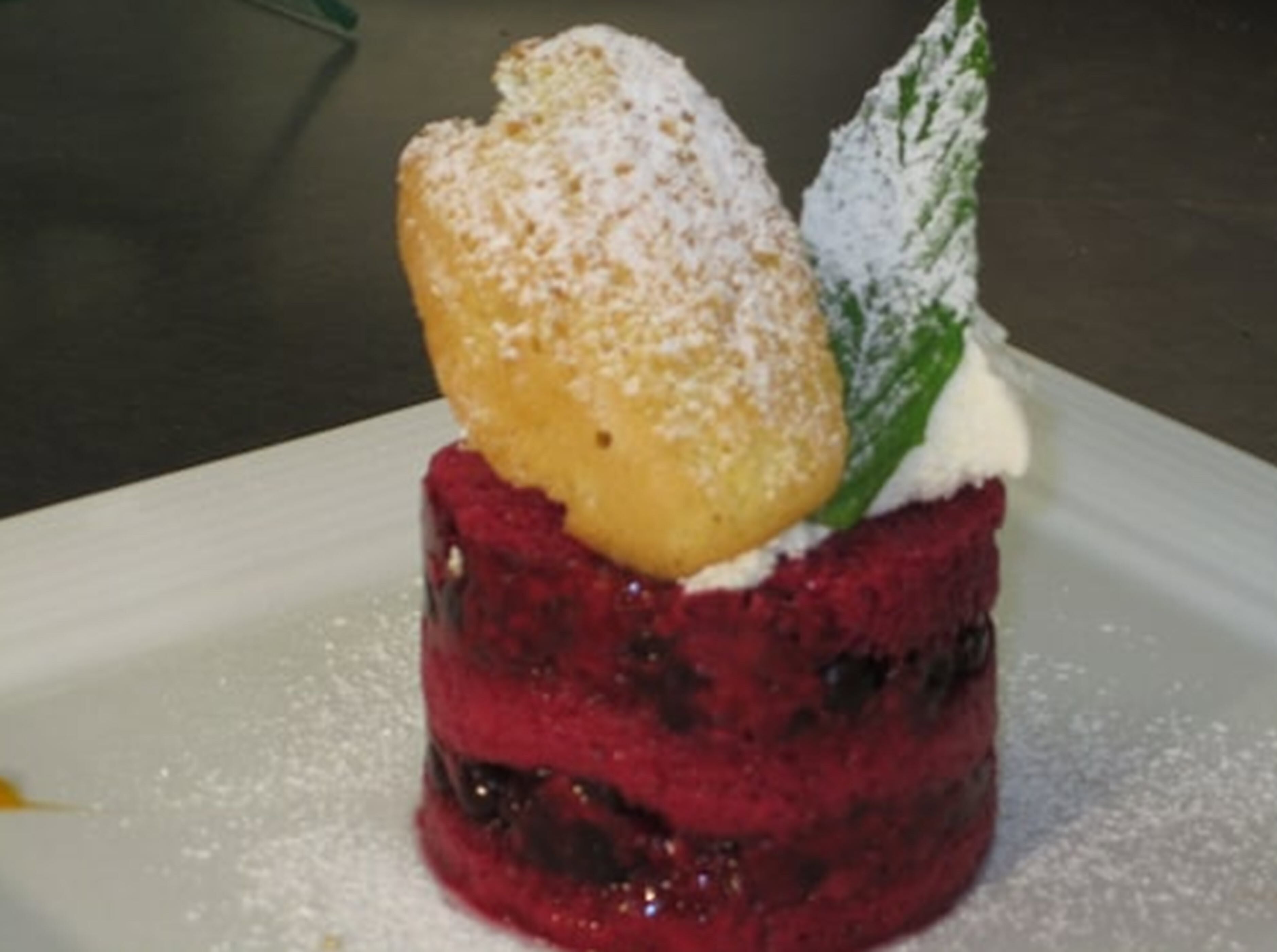 Un postre con cobertura de azúcar glas y una hoja como adorno en un plato.