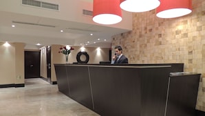 Un mostrador de recepción con un reloj, un jarrón con flores y una pared de madera.