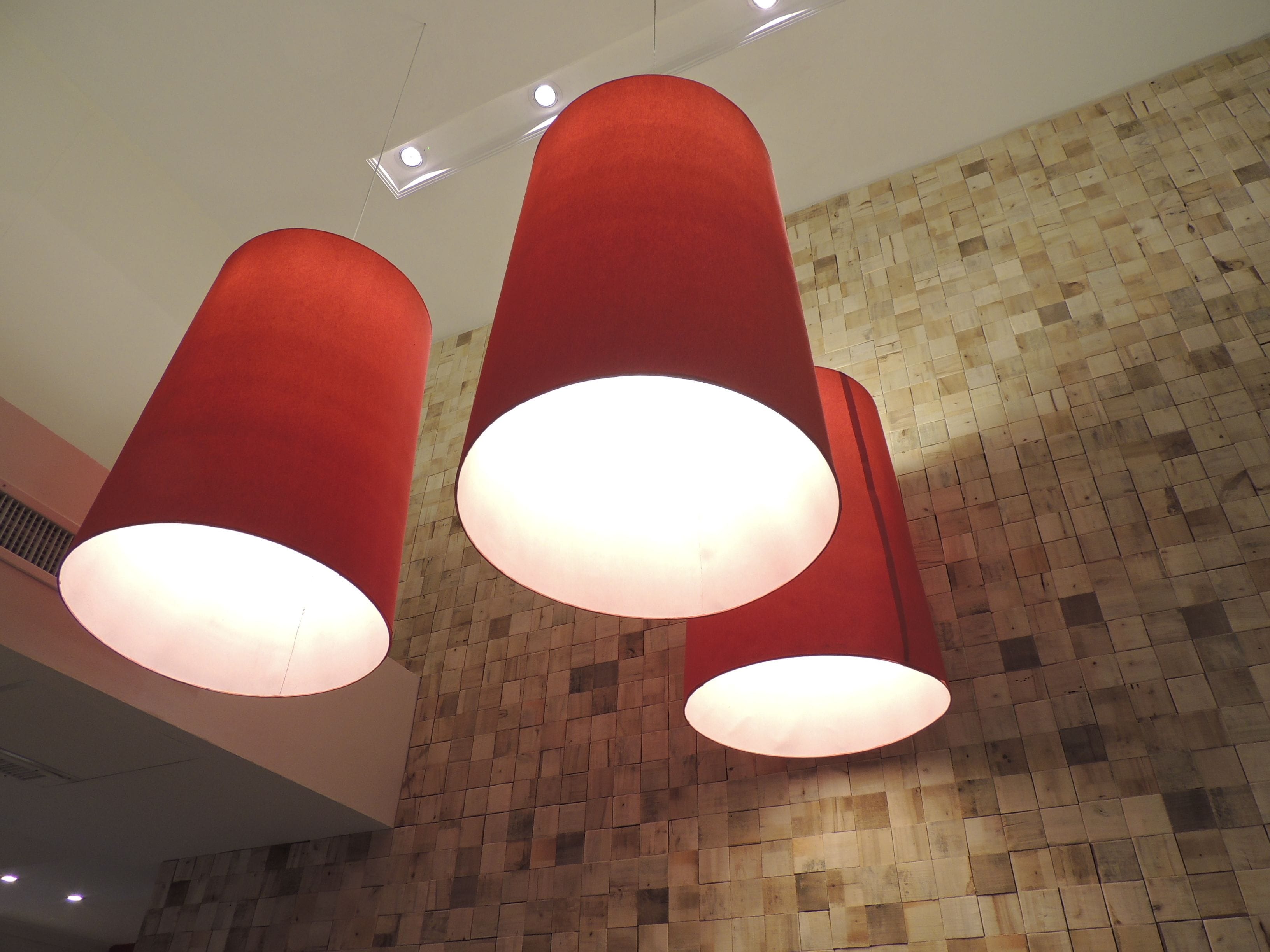 A modern interior with wooden flooring and red cylindrical light fixtures.