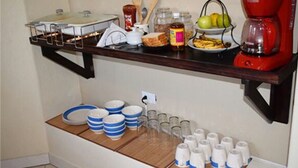 Un bar pour prendre le petit-déjeuner, équipé d’une machine à café, d’un panier de fruits et de divers aliments pour le petit-déjeuner.