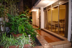 Un espacio al aire libre bien iluminado con plantas en macetas y un patio con sillas y mesas.