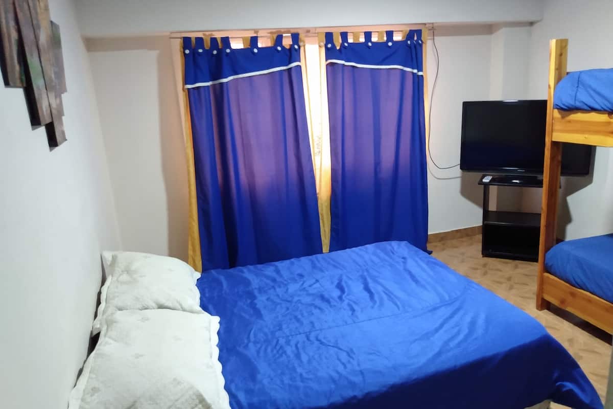 Ein Zimmer mit Etagenbett, Fernseher auf einem Schrank und einem Vorhang mit Holzrahmen.