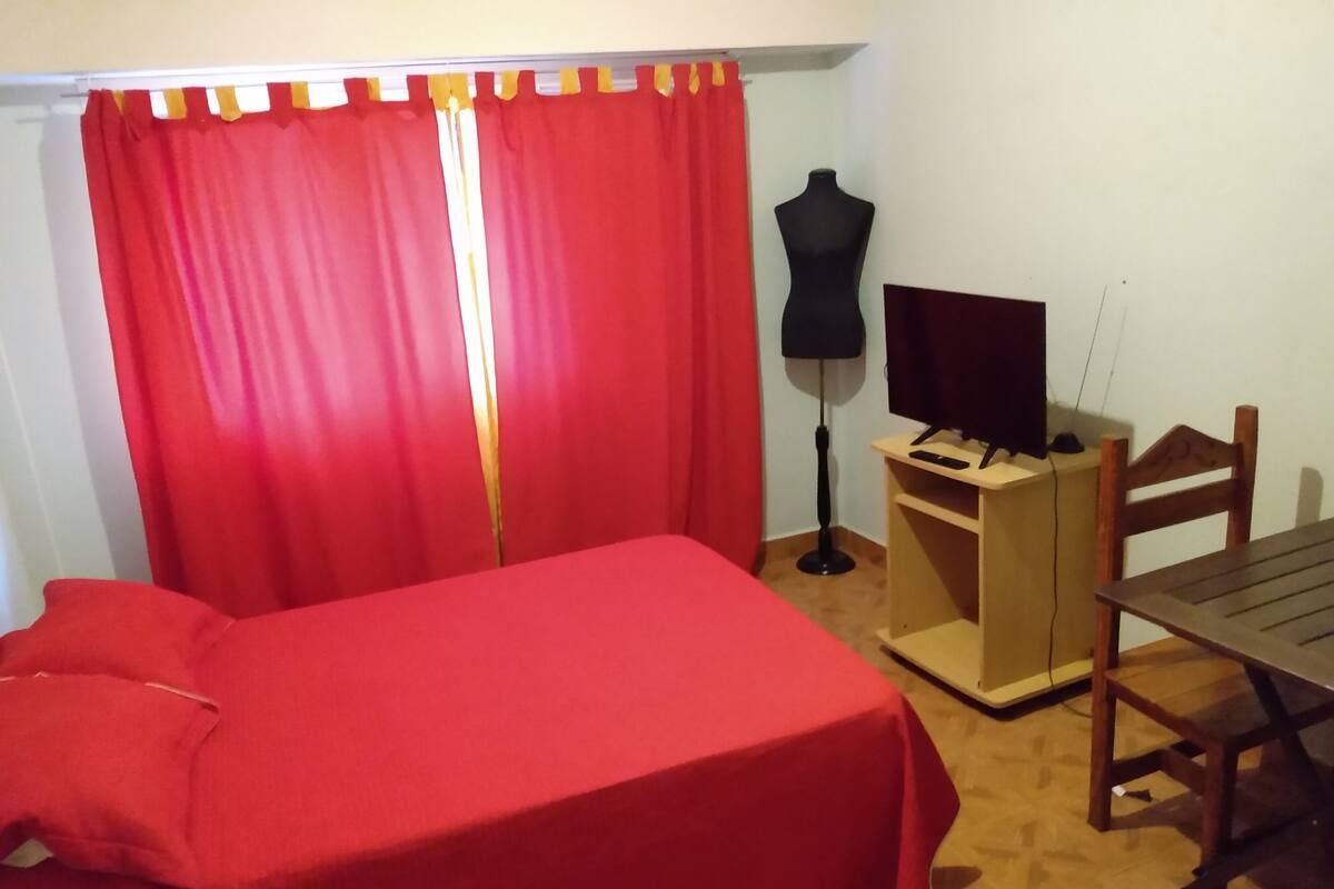 Ein Zimmer mit einem Bett, einem Schreibtisch, einem Stuhl, einem Fernseher und einer Mannequin.