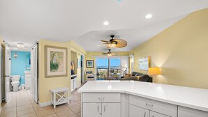 A spacious kitchen with a large island, a dining area with a view, and a bathroom with a toilet and sink. - 🌅 Prime View Condo — Gulf Strand Resort, St. Pete Beach (St Pete Beach)
