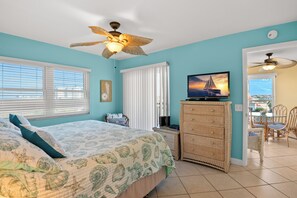Camera da letto con un letto, televisione, ventilatore a soffitto e vista sull'esterno.