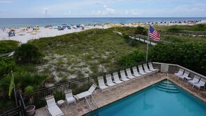 A pool area with lounge chairs and an American flag.