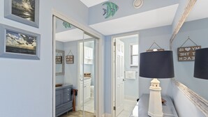 A hallway with a mirror, a lamp, and a door leading to a bathroom.