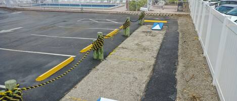 Un área de estacionamiento con barreras a rayas amarillas y negras, una flecha direccional azul y una valla blanca.