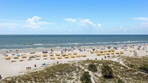 Ein Strand mit vielen gelben Sonnenschirmen und Menschen, die das Meer genießen.