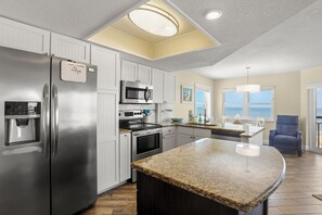 A modern kitchen with a stainless steel refrigerator, built-in microwave, and granite countertop.