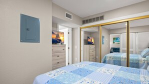A bedroom with a bed, a wardrobe, a mirror, and a door.