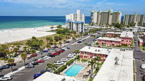 A hotel with a rooftop pool, a beach view, and a parking lot.