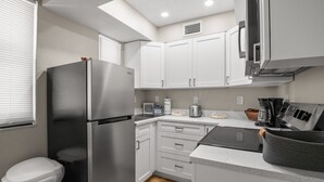 A compact kitchen with white cabinets, a stainless steel refrigerator, a microwave, and a toaster.
