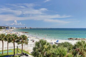 Ein Strand mit Palmen, Sonnenschirmen und Menschen.