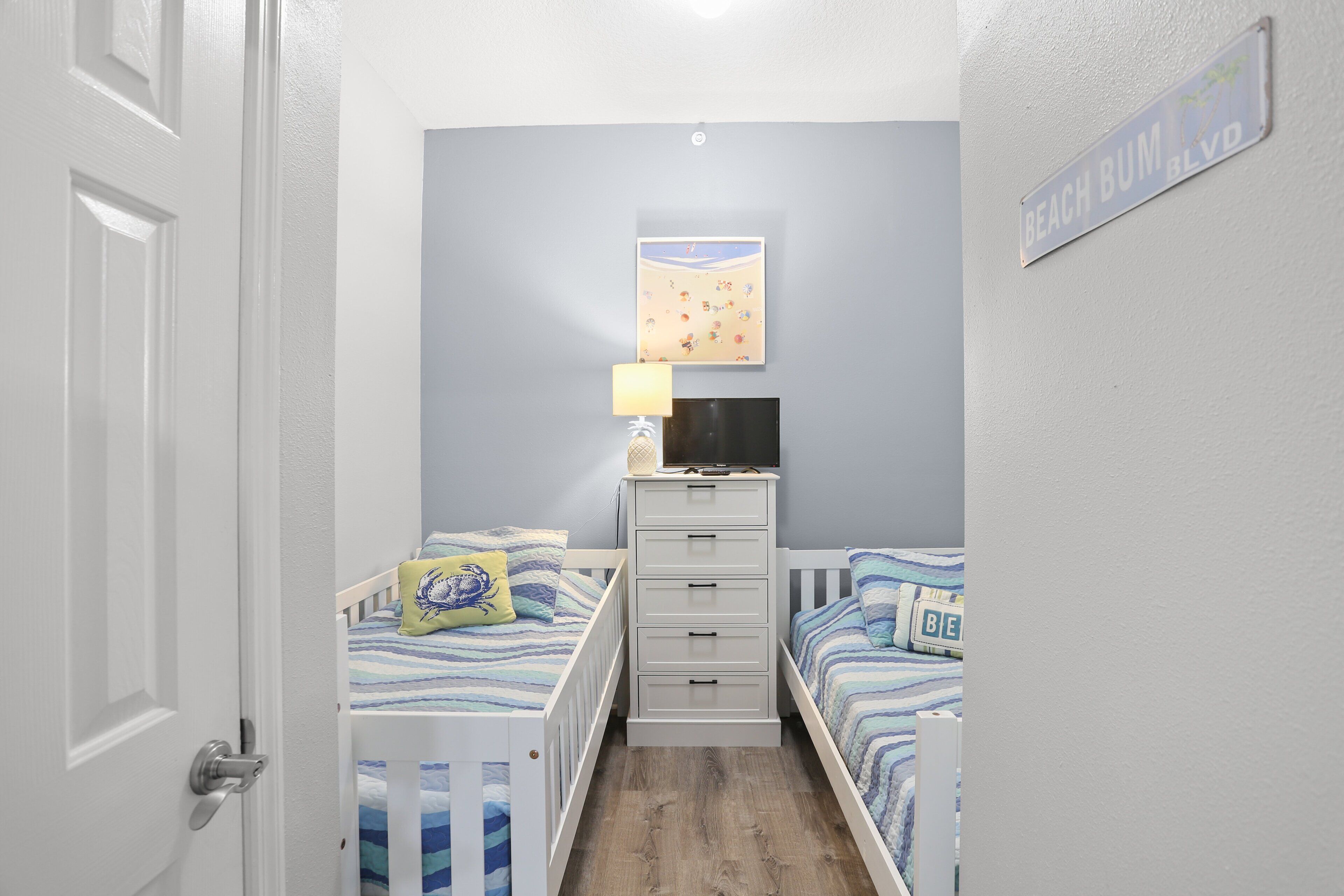 Ein Schlafzimmer mit zwei Betten, einem Fernseher, einem Schminktisch und einem an der Wand hängenden Bild.