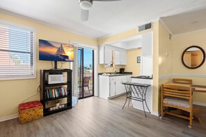 A modern kitchen with white cabinets, a microwave, and a dining area with a table and chairs.
