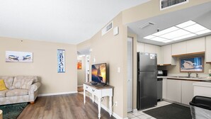 Um espaço compacto com cozinha compacta, sofá, televisão e mesa pequena.