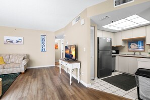 A compact living space with a kitchenette, a sofa, a TV, and a small table.