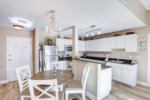 A modern kitchen with white cabinetry, a central island, stainless steel appliances, and a chandelier. - 🌅 Madeira Bay Resort #602 – Elegant Two-Bedroom Condo with Dual Balconies (Madeira Beach)