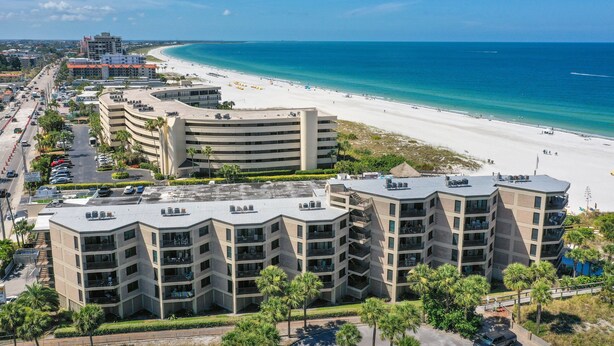 Un hôtel situé en bord de mer, avec plusieurs étages, des balcons et une vue sur la plage et l’océan.