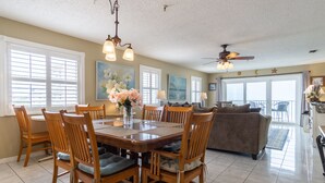 A spacious dining area with a wooden table and chairs, a ceiling fan, and large windows with blinds. - Sea Breeze 301 | Corner Unit with Dual Balconies & Sweeping Gulf-to-Bay Views (Madeira Beach)