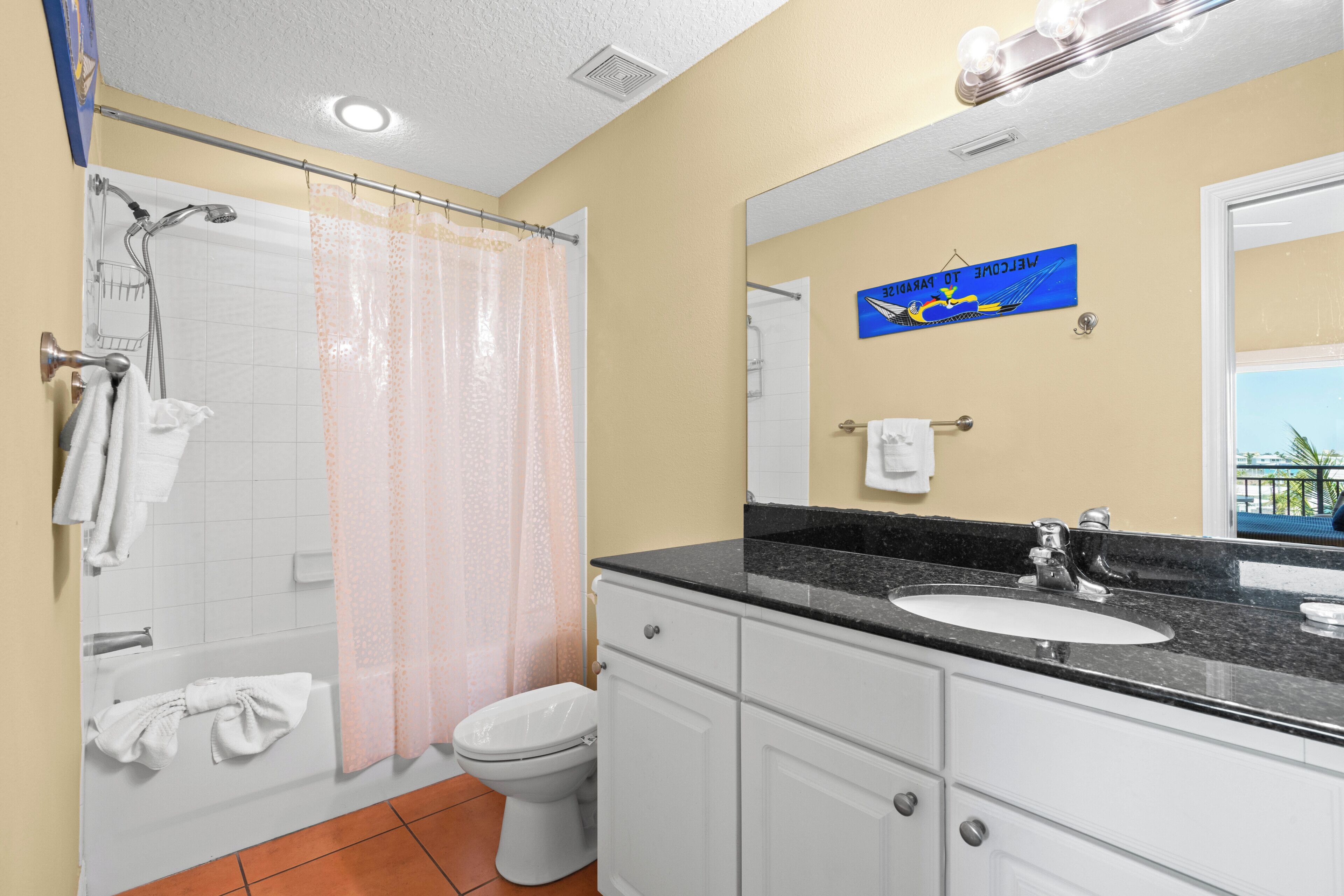 A bathroom with a shower, toilet, sink, and a towel rack.