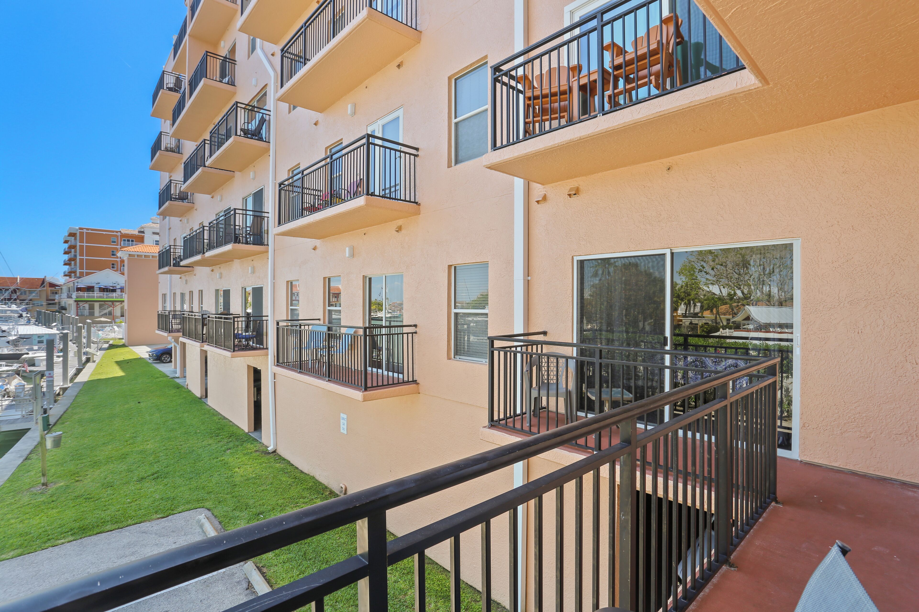 A multi-story residential building with balconies, a green lawn, and a clear view of the surrounding area.