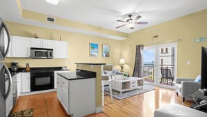 A compact living space with a kitchenette, a dining area, a sofa, and a balcony with a view. - ♿ Madeira Bay Resort #402 – Spacious, Handicap-Friendly One-Bedroom Retreat Near the Beach (Madeira Beach)