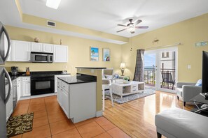 Un espace de vie compact comprenant une kitchenette, un coin repas, un canapé et un balcon avec vue.