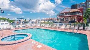 A swimming pool with lounge chairs and a hot tub, surrounded by a fence. - ♿ Madeira Bay Resort #402 – Spacious, Handicap-Friendly One-Bedroom Retreat Near the Beach (Madeira Beach)
