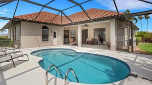 Ein Schwimmbad mit Glasveranda, rotem Flachdach und einer Terrasse mit Stühlen und Tischen.