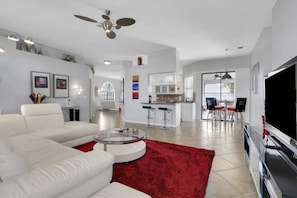 Una sala de estar moderna con un sofá blanco, una mesa de centro de vidrio y un tapete rojo.