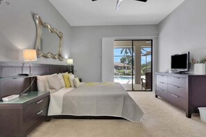 Quarto moderno com cama, mesas de cabeceira, televisão e vista para o exterior.