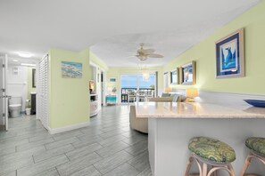 A spacious kitchen with a large island, a dining area with chairs, and a view of the ocean.